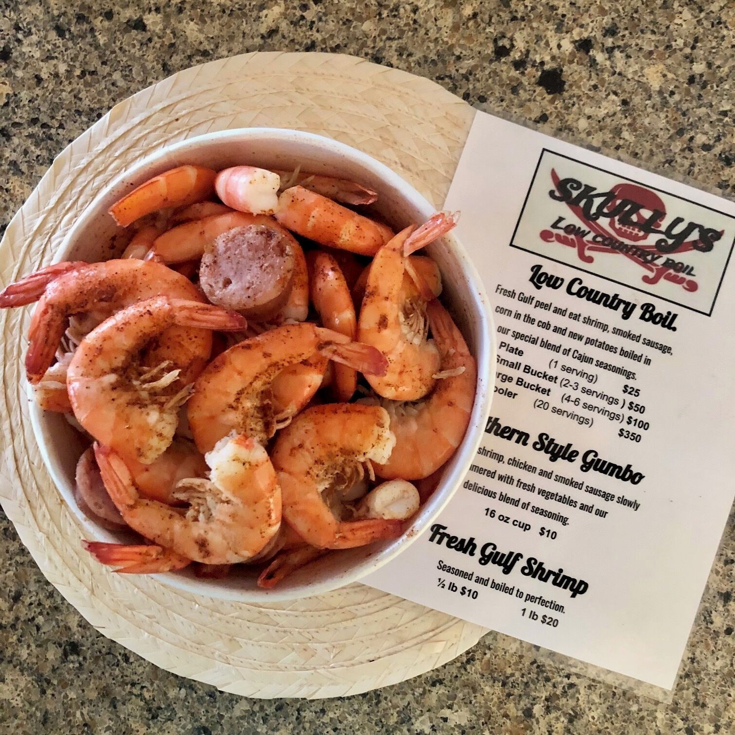 A bowl of shrimp and sausage on a woven mat with a menu listing dishes like 'Low Country Boil' and 'Fresh Gulf Shrimp'.