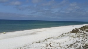 Een strand met wit zand en helderblauw water.