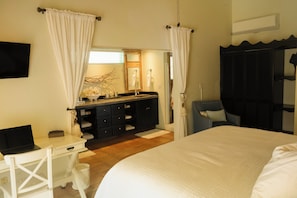 A bedroom with a large bed, a desk with a laptop, a vanity with a mirror, and a wardrobe. - Endless Summer Villa - Luxury by the Sea (Cane Garden Bay)