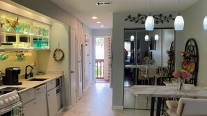 A kitchen with white cabinets, a stove, and a dining area with a table and chairs. - Quiet Island getaway 30% off Fall/Winter stays! Private Fishing Pier, PERFECT! (Navarre)