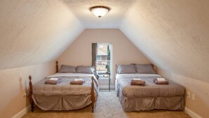 A room with two beds, a small table, and a window. - Spacious 4-BR Home – Open Concept, Deck & Parking! (Pittsburgh)