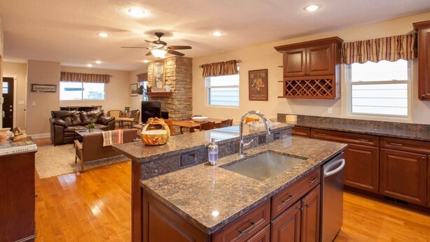 A spacious kitchen with granite countertops, wooden cabinets, and a central island. - Spacious 4-BR Home – Open Concept, Deck & Parking! (Pittsburgh)