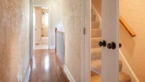 A hallway with a carpeted staircase leading to a room. - Spacious 4-BR Home – Open Concept, Deck & Parking! (Pittsburgh)