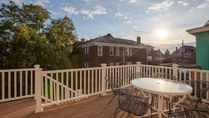 A wooden deck with a white railing, a round glass table, and metal chairs. - Spacious 4-BR Home – Open Concept, Deck & Parking! (Pittsburgh)