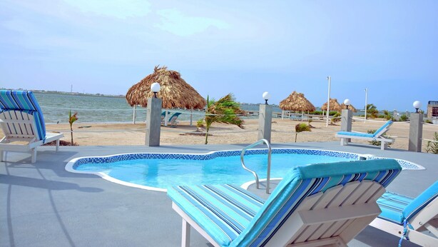 A pool area with lounge chairs and a view of the beach.