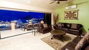 A spacious living room with a large window overlooking a cityscape at night.