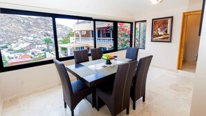 A dining area with a large window, a table with chairs, and a vase with flowers.