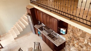 A kitchen with dark wooden cabinets, a granite countertop, and a stainless steel sink.
