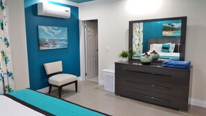 A bedroom with a bed, a chair, a dresser, a mirror, and a painting on the wall. - Flamingo Villa in quiet & secure gated development close to airport, beaches  (Canaan)