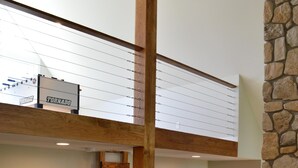 A multi-level interior with wooden flooring, a stone accent wall, and a loft area with a sign reading "TORNADO". - Get back to nature and experience lake life in style when you stay at our house (Albion)