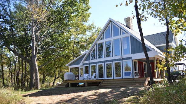 A cabin with a large deck, surrounded by trees. - Get back to nature and experience lake life in style when you stay at our house (Albion)