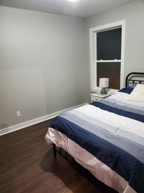 A bedroom with a bed, a nightstand, a lamp, and a window. - Get back to nature and experience lake life in style when you stay at our house (Albion)
