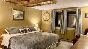 A bedroom with a bed, nightstands, a lamp, a window with curtains, a wall clock, and a framed picture. - Beautiful 3 BR ski In Trailside condo.  Steps away from WaterPark & Ice Rink  (Jay)