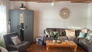 Un salon avec un plafond en bois, un canapé gris et une table basse en bois.