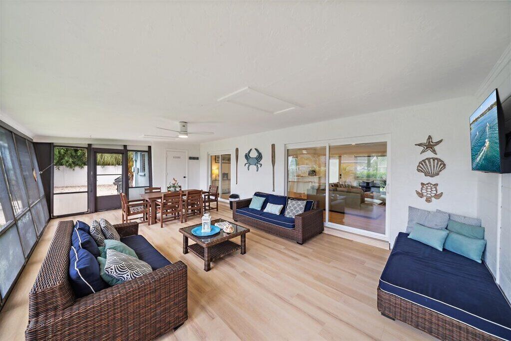 A spacious living area with a sofa set, a coffee table, and a dining table. There are decorative wall art pieces and a television mounted on the wall.