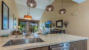 Een moderne keuken met een groot eiland, roestvrijstalen apparatuur en hanglampen.