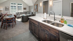 A modern kitchen with dark wood cabinets, a large island, and a double sink. - La Conner, Tillinghast Residence E #401 (La Conner)