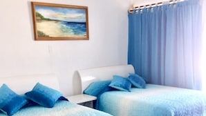 Una habitación con dos camas, un cuadro en la pared y una ventana con cortinas.