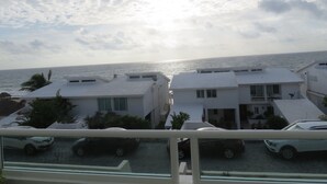 Un hotel costero con edificios blancos, vista al mar y coches estacionados en primer plano.