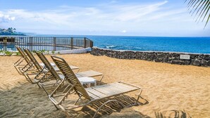 Une plage avec des transats et un muret en pierre.