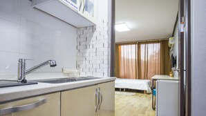 A compact kitchen with a sink, cabinets, and a refrigerator. - Kyung-po Stone Valley (Gangneung)