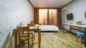 A room with a bed, a desk, a chair, a TV, and a window with curtains. - Kyung-po Stone Valley (Gangneung)