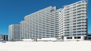 Ein großes, mehrstöckiges Hotel mit Balkonen direkt an einem Sandstrand.