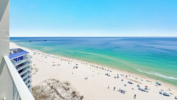 Ein Strand mit einem Steg, klarem blauen Wasser und Blick aufs Meer.