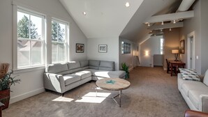 A spacious living area with a large gray sectional sofa, a round coffee table, and a dining area with a table and chairs. - La Conner, Tillinghast Residence A #400 (La Conner)