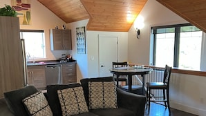 A loft-style living space with a high ceiling, a dining area, and a kitchen. - Chalet Style Suite on Peachland Acreage (Peachland)