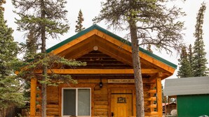 Une cabane en rondins avec un toit vert et une pancarte indiquant « Cabane de l’orignal ».