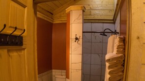 Une salle de bain avec des toilettes, une douche et une porte en bois.