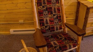 Une chaise en bois avec un siège et un dossier rembourrés, un panier tressé et un tableau représentant un bélier accroché au mur.