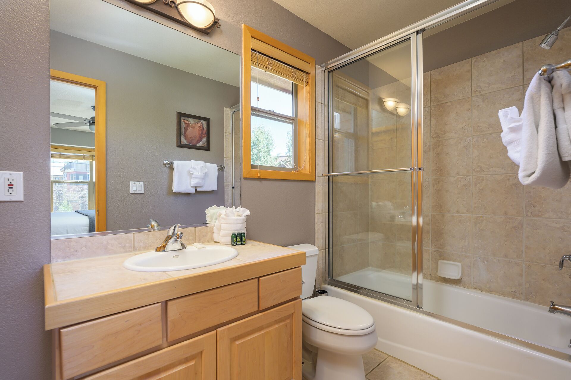 A bathroom with a sink, mirror, and a glass-enclosed shower.