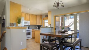 Una cocina moderna con armarios de madera, una isla central con taburetes, un microondas, estufa y cafetera.