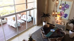 A spacious dining area with a large table and chairs, a view of the outdoor deck through large windows, and a painting of flowers on the wall. - Three bed loft at Private Residence Club (Playa del Carmen)