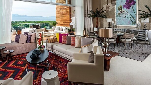 A spacious living room with a large window, a sofa set, a dining area, and a painting of flowers. - Three bed loft at Private Residence Club (Playa del Carmen)