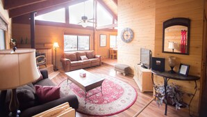 A cozy cabin interior with a sofa, coffee table, and a fireplace.