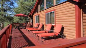 A wooden cabin with a deck, red railings, and outdoor furniture.