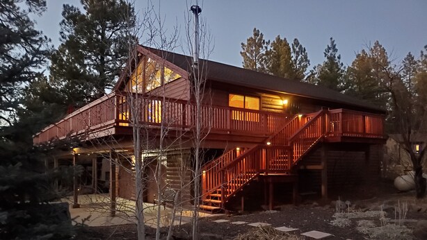 A log cabin with a wooden deck and a staircase leading to a second level.