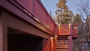 A wooden staircase leading to a garage with a red railing and lights.