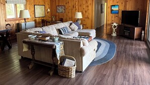 A wooden-paneled room with a sofa, a television, and a wicker basket.