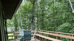 Eine Holzterrasse mit Tisch und Stühlen, umgeben von Bäumen.