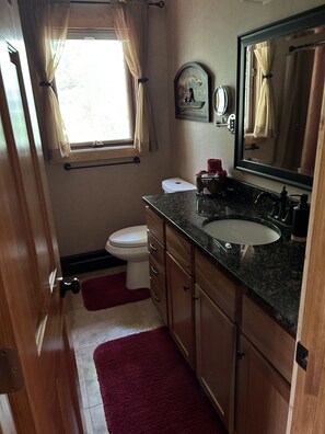 A compact bathroom with a toilet, sink, and mirror. - Private Yet Middle-of-the-Action Gull Chain Home. (Nisswa)