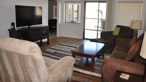 A living room with a flat-screen TV, a sofa, a coffee table, and a lamp. - Relax in beautiful and quiet Scottsdale condo. Heated pool/hot tub (Scottsdale)