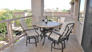 A balcony with a round table and four wicker chairs, a bottle of wine, and two wine glasses. - Relax in beautiful and quiet Scottsdale condo. Heated pool/hot tub (Scottsdale)
