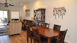 A dining area with a wooden table and chairs, a bookshelf, and a decorative wall piece. - Relax in beautiful and quiet Scottsdale condo. Heated pool/hot tub (Scottsdale)