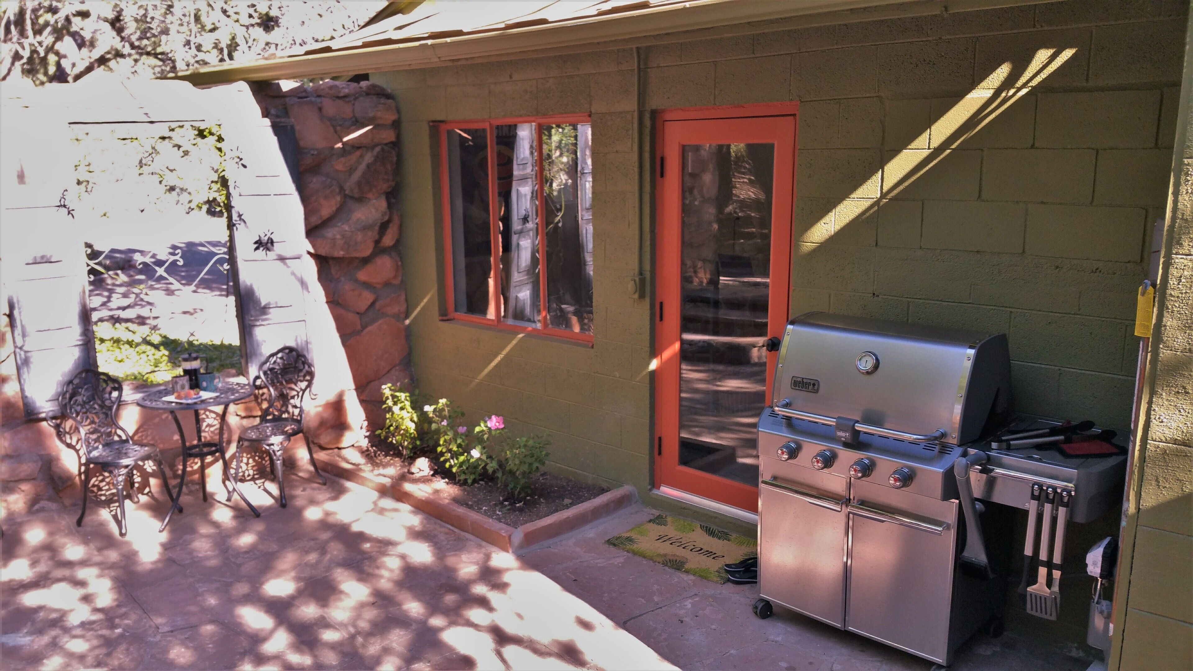 A patio with a grill, outdoor seating, and a stone wall.