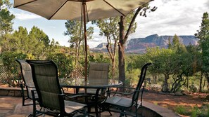 An outdoor patio with a round table and chairs, an umbrella, and a scenic view of mountains and trees. - 2-Bedroom, Sleeps 6 - Vacation home near Tlaquepaque Arts and Crafts Village (Sedona)