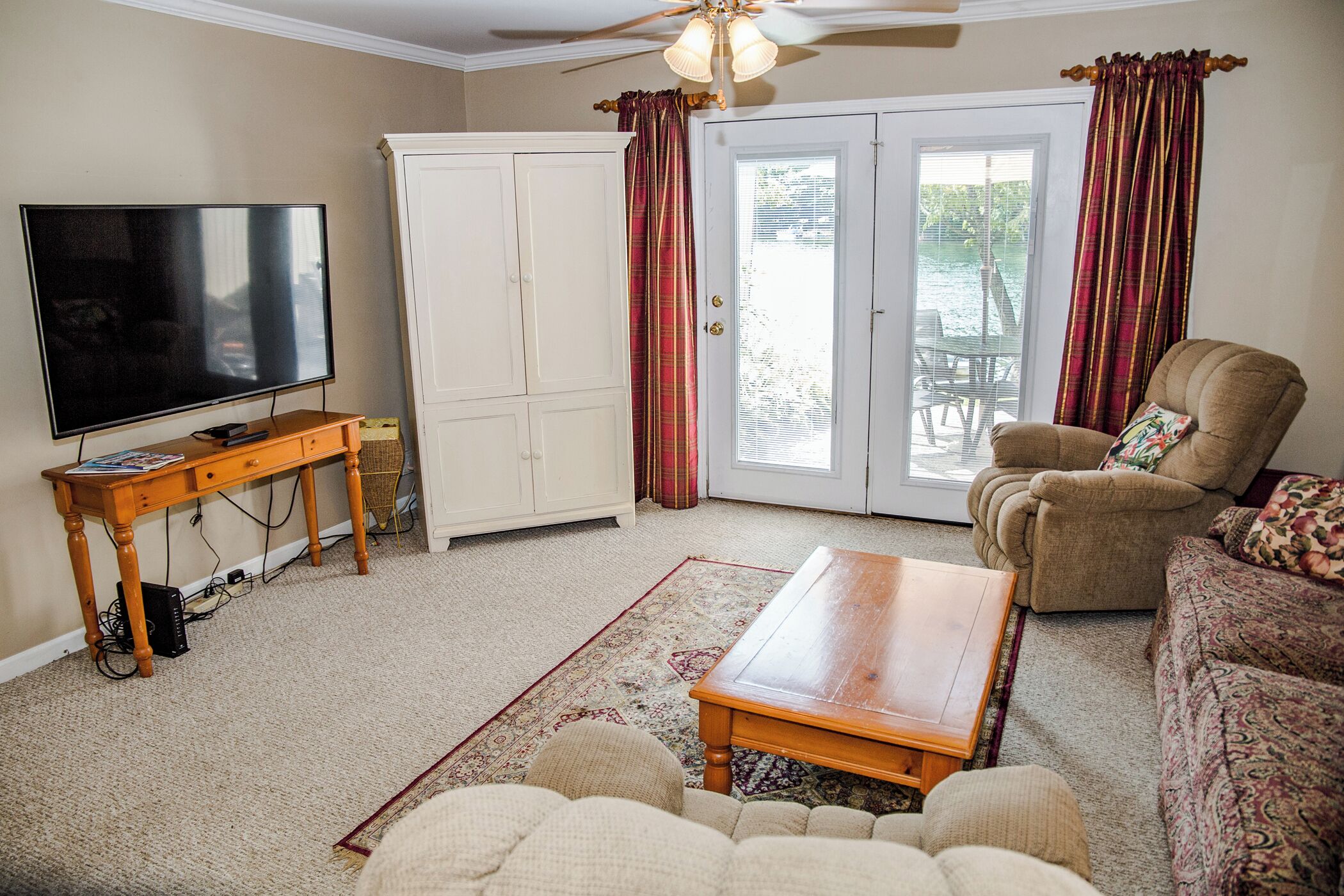 A living room with a television, a cabinet, a sofa, a coffee table, and a patterned rug.